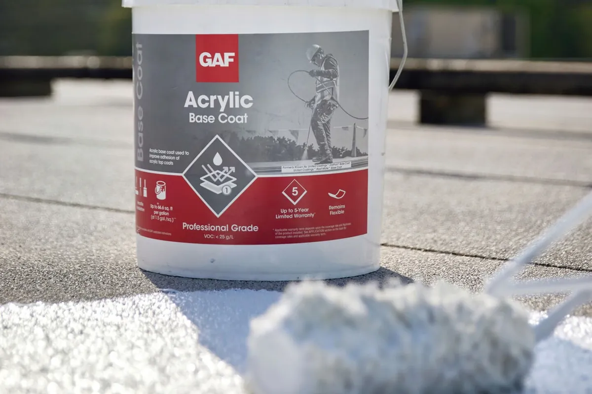 Acrylic base coat being rolled onto a roof