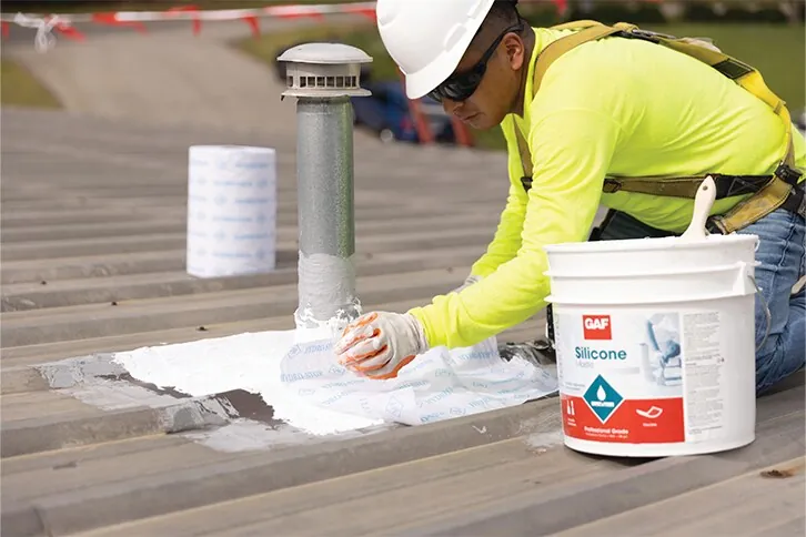 Pipe penetration on a metal roof being sealed with silicone mastic and fabric