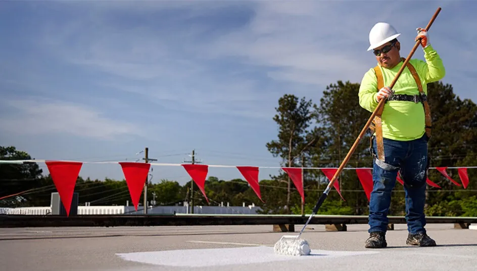 Crew rolling a white coating onto a commercial roof