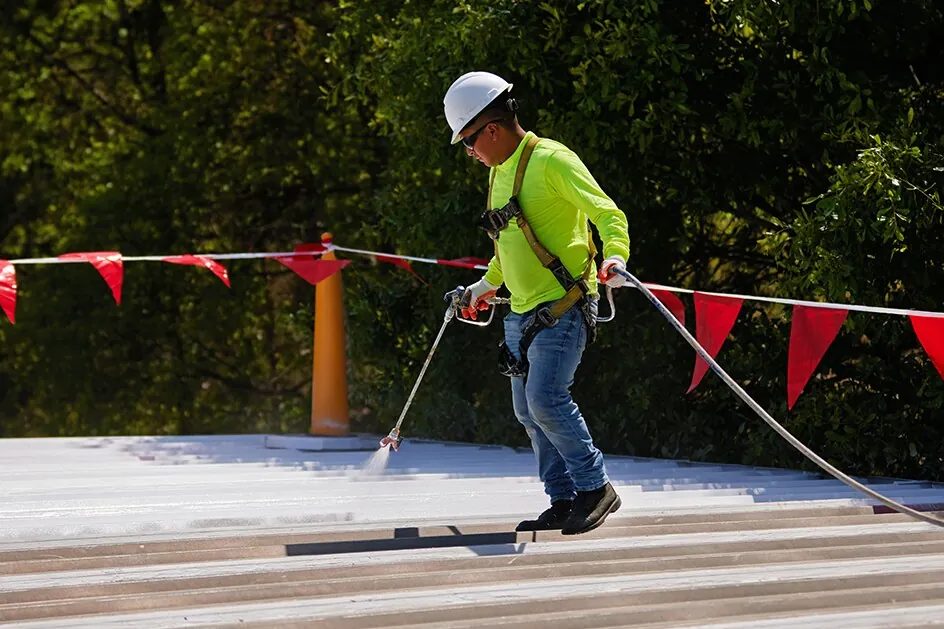 Silicone coating being sprayed over a metal roof